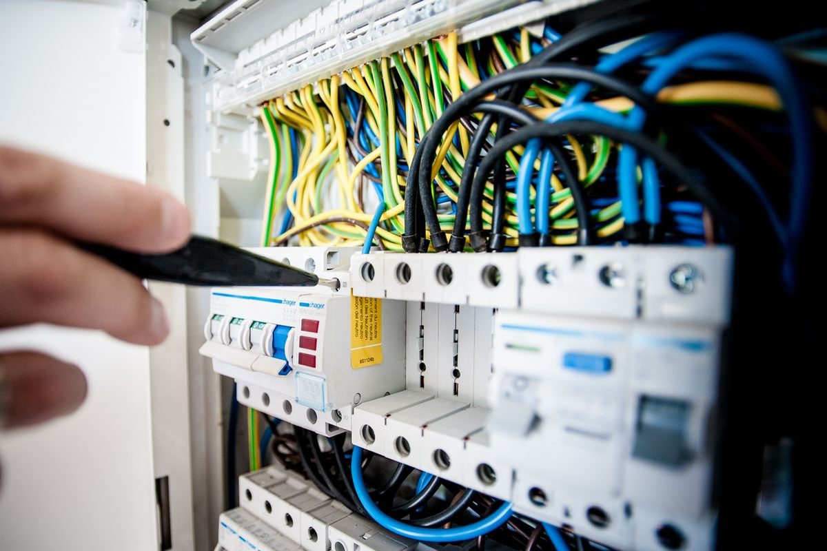 Hand adjusting a screw on a circuit breaker panel